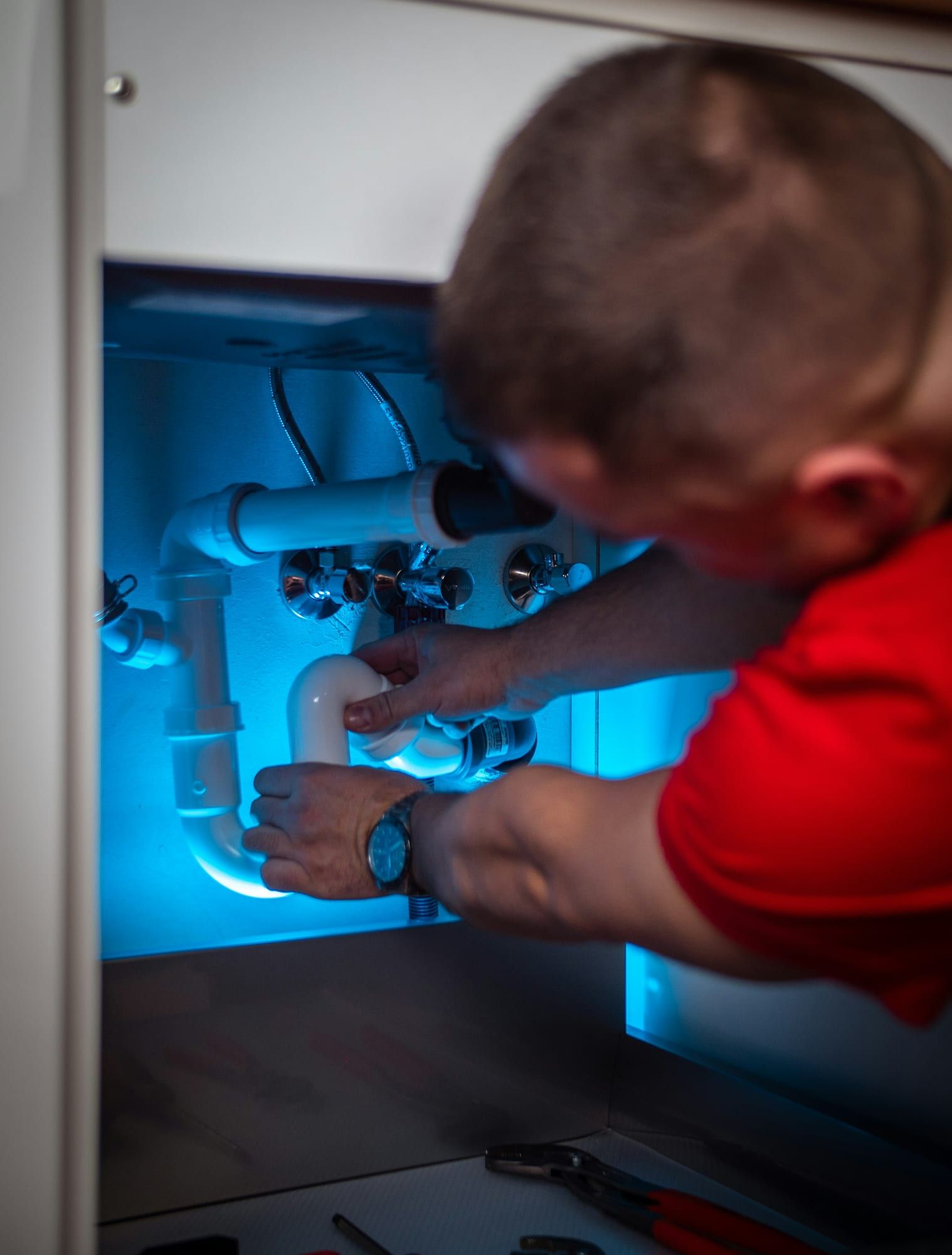 Plombier travaillant sur la tuyauterie sous un évier