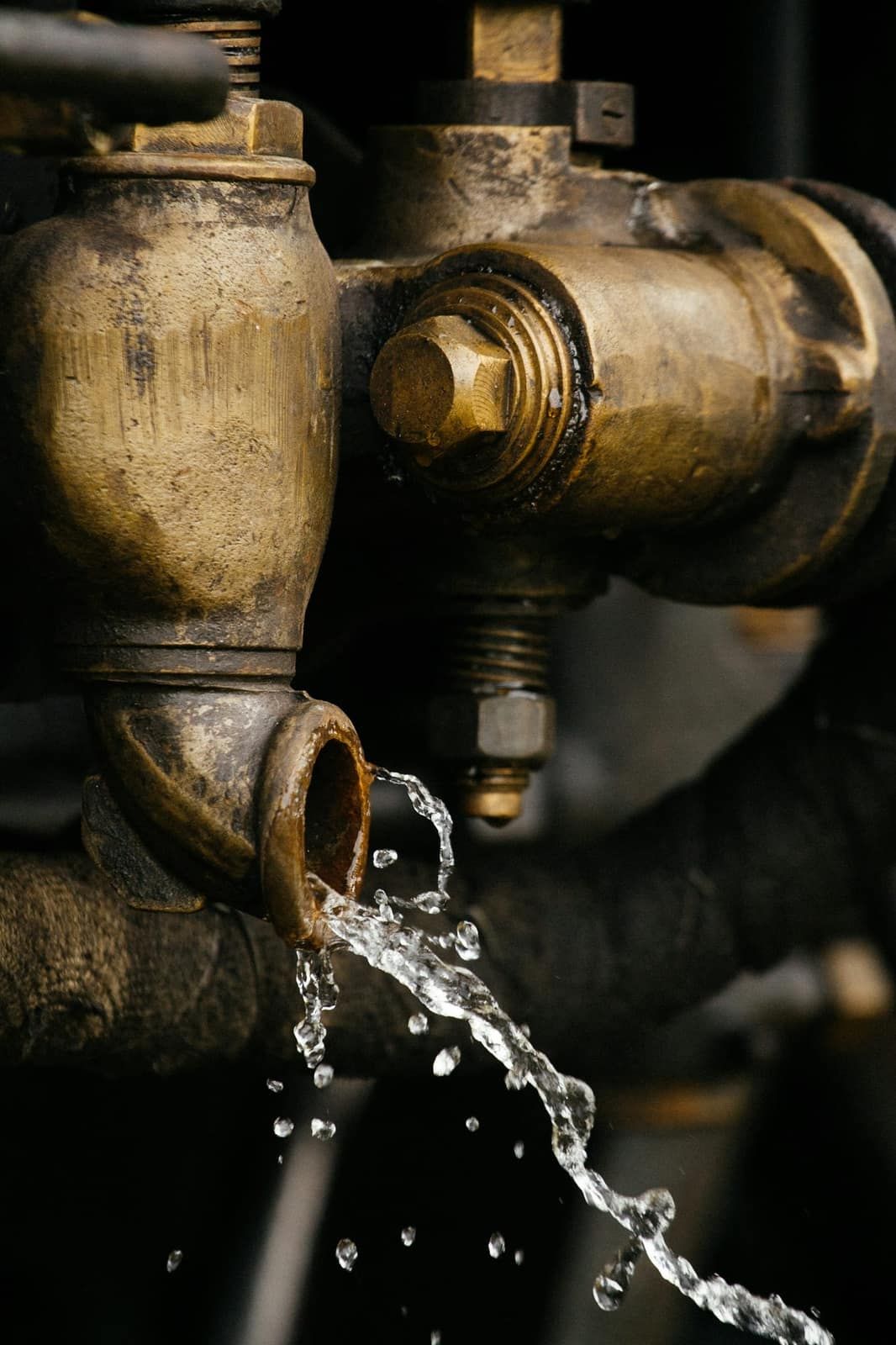 Robinet ancien en laiton d’où s’écoule un filet d’eau