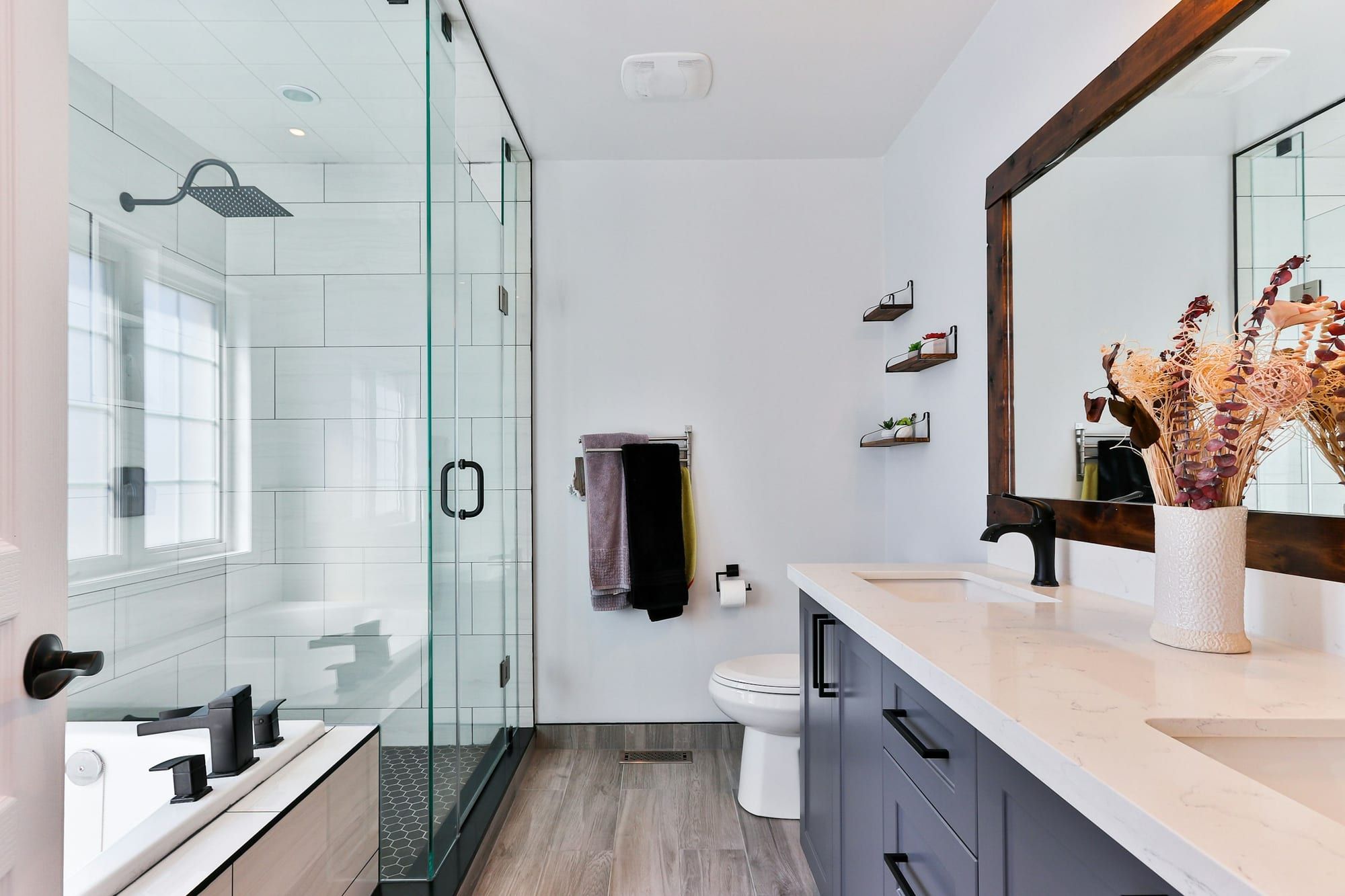 Salle de bain rénovée avec douche vitrée, parquet et double vasque